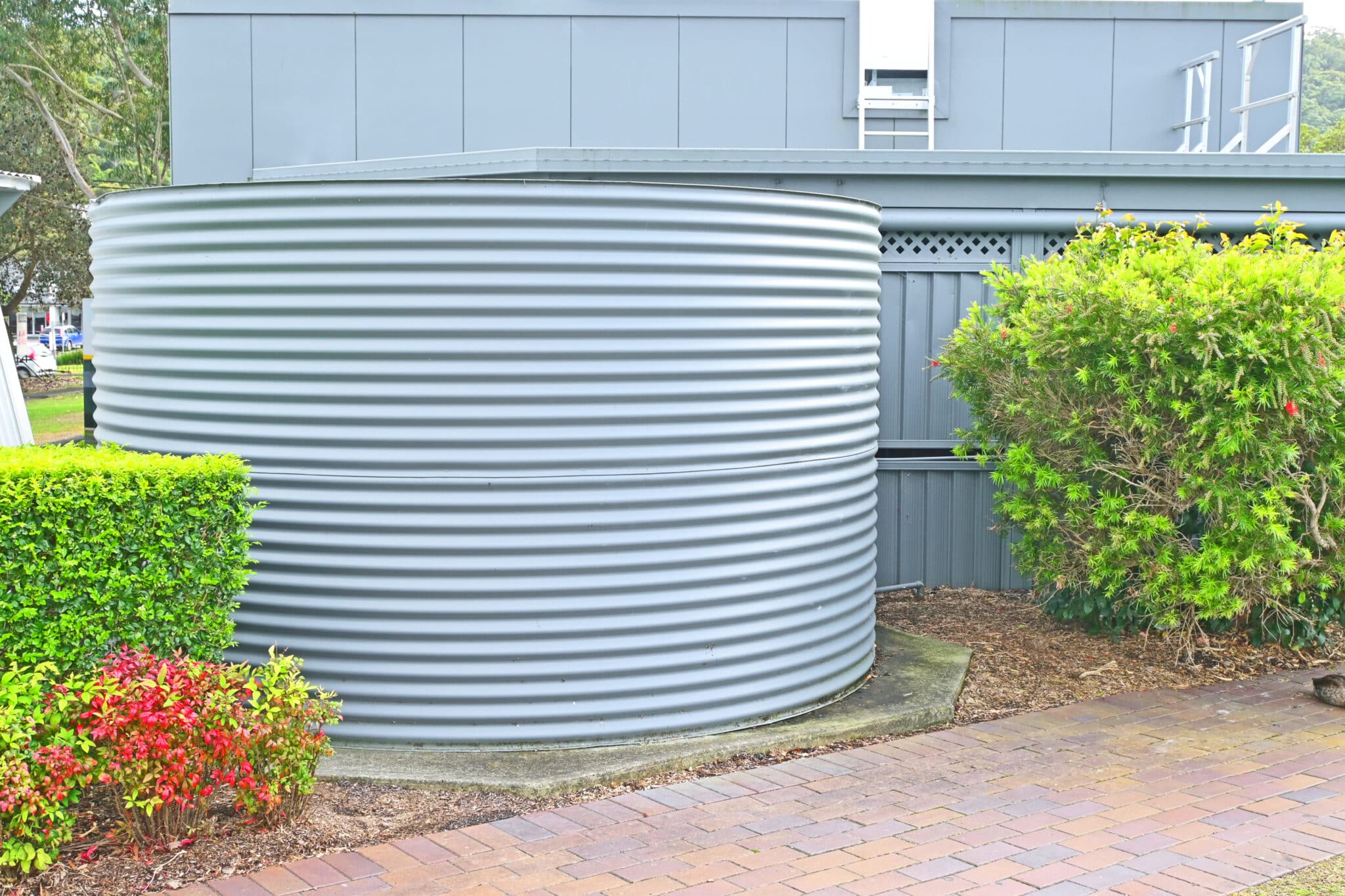Large rainwater storage tank behind a building, Zero-Energy Plumbing Systems.