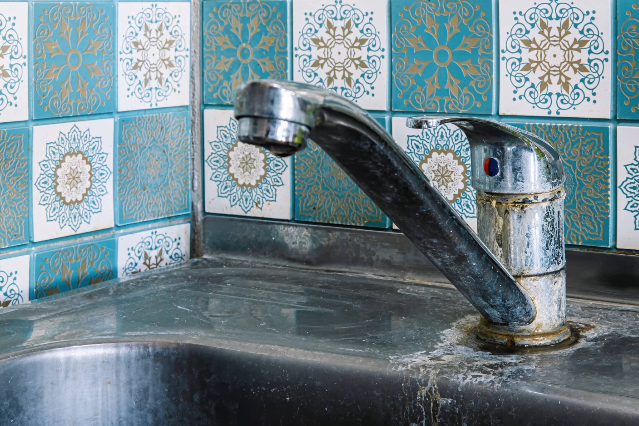 Old rusty sink faucet in kitchen. rust streaks, calcium scale, hard water, Low Water Pressure.